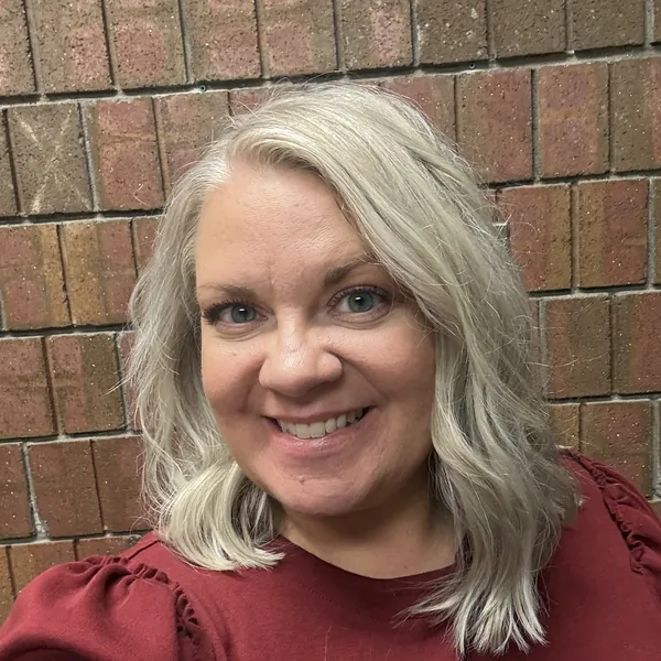 Becca Cluff, Bestie Squad member, smiling in a red top